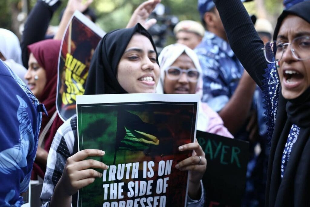 Group of young people protesting, holding signs that read "Truth is on the side of oppressed."